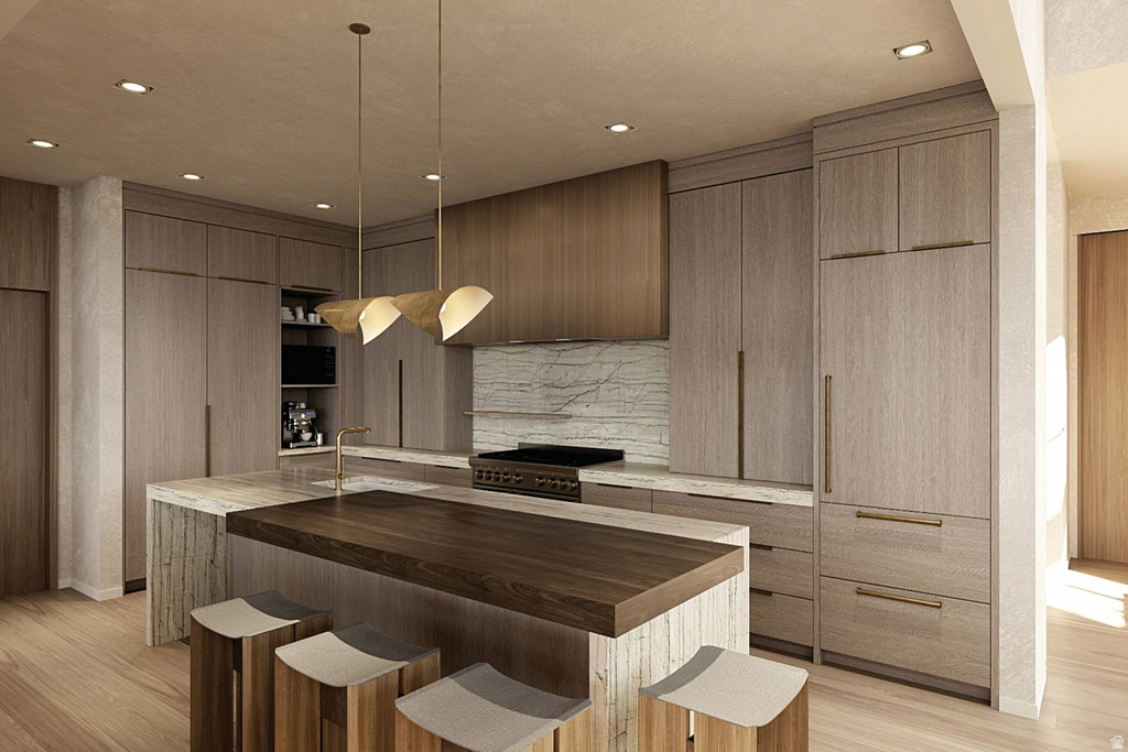 Kitchen featuring custom light wood-grain cabinetry, a large kitchen island with a dark wood-finish countertop, and integrated appliances