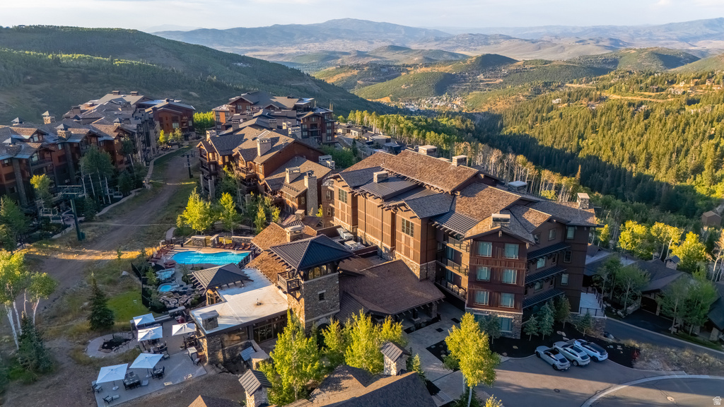 Mountain resort property featuring a large multi-story building, exterior swimming pools, a paved driveway, and surrounding forested hills