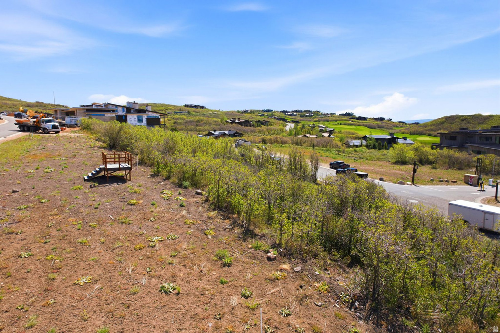 Spacious open lot featuring a clear building site, a temporary wooden observation deck, and established shrubbery along the perimeter