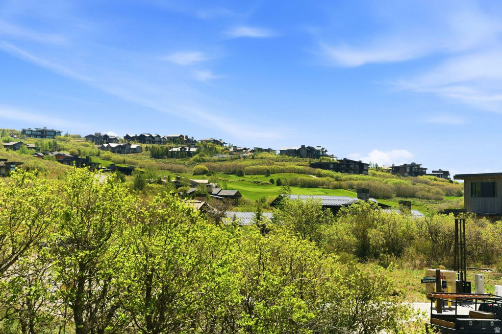 Hillsides featuring verdant foliage and distant residences under a clear sky