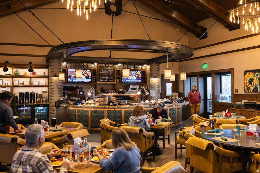 Spacious dining area featuring exposed wooden ceiling beams and multiple chandelier light fixtures