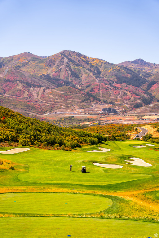 Expansive golf course featuring manicured greens and sand traps, with a backdrop of vibrant, autumn-colored mountains