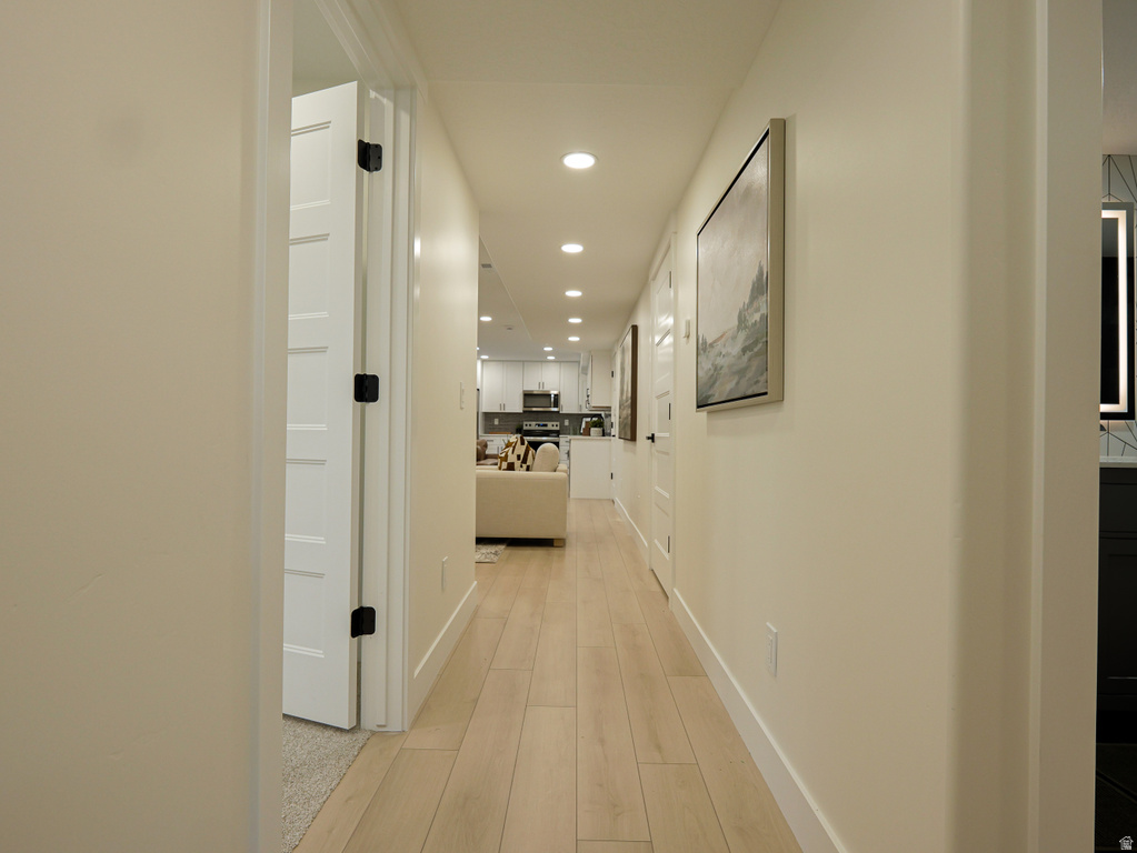 Hallway featuring light wood-finish flooring, recessed lighting, and white baseboards