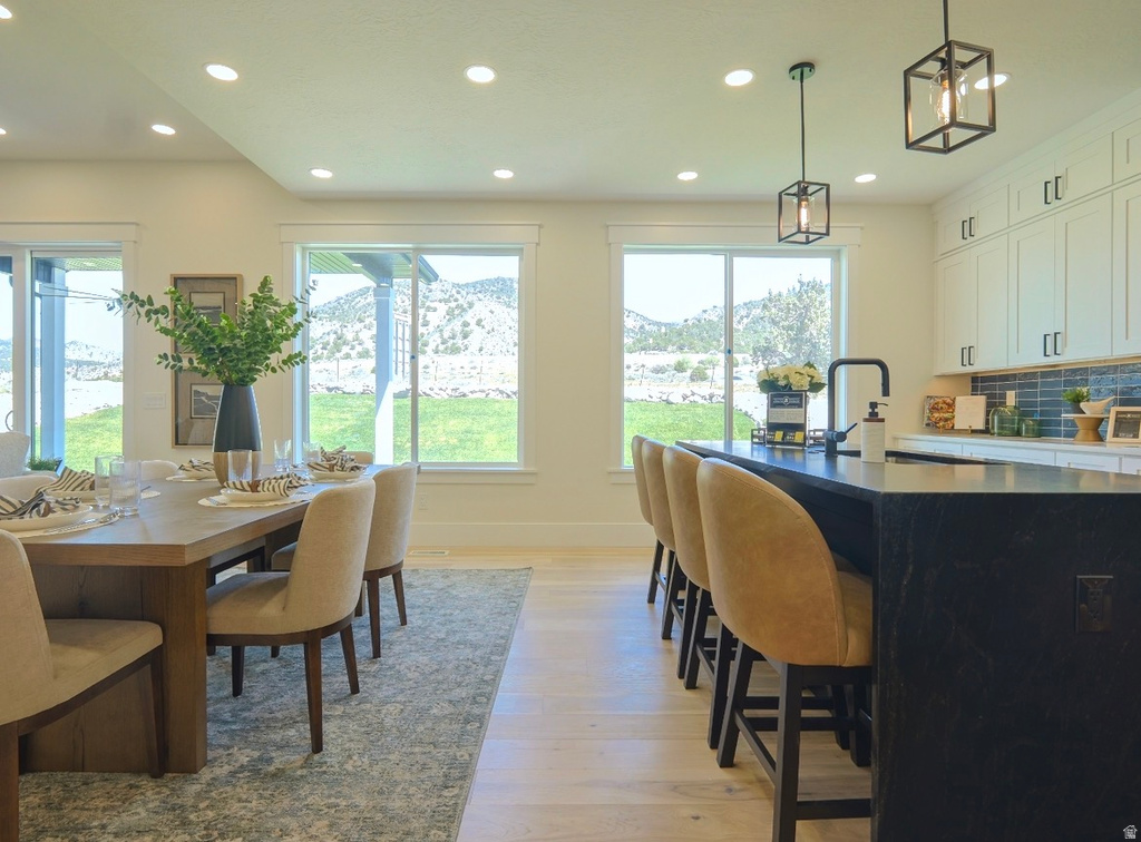 Open-concept kitchen and dining area featuring light wood-finish flooring, recessed lighting, and a large dining table