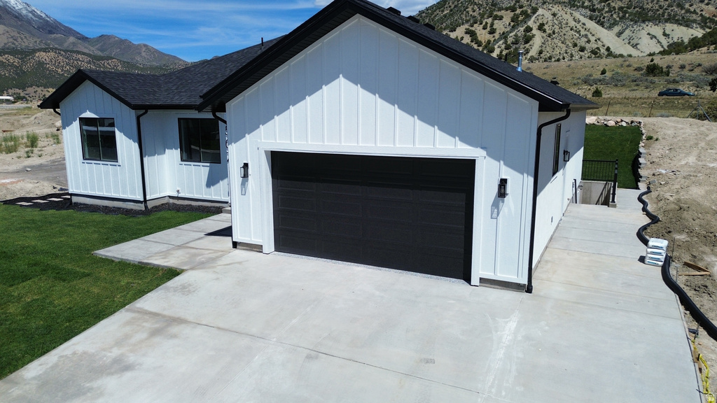 Modern farmhouse-style exterior featuring white board and batten siding, a dark asphalt shingle roof, and a two-car garage with a black door