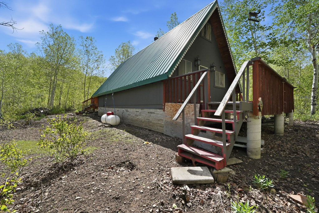 A-frame structure featuring a green metal roof, dark gray corrugated siding, and a stone-clad foundation