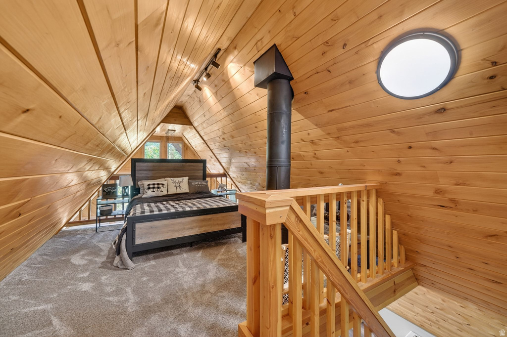Attic space with wood-finish paneling, a round skylight, track lighting, and a prominent dark stove pipe