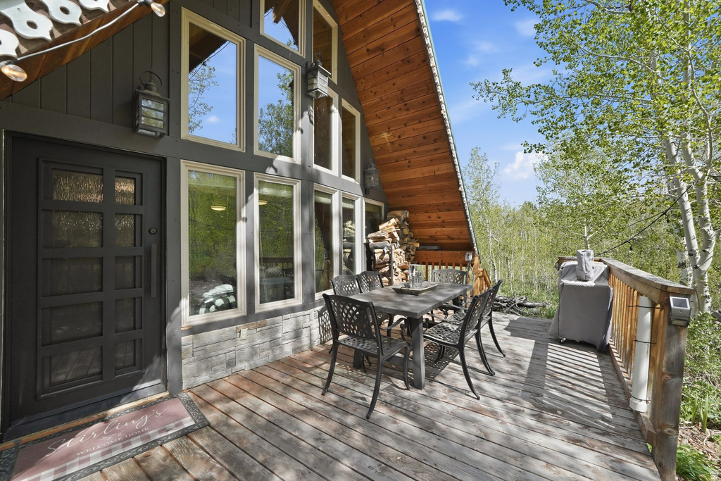 Exterior deck featuring dark gray siding, a prominent dark door, large windows, a natural wood-finish sloped roof, and a wooden railing