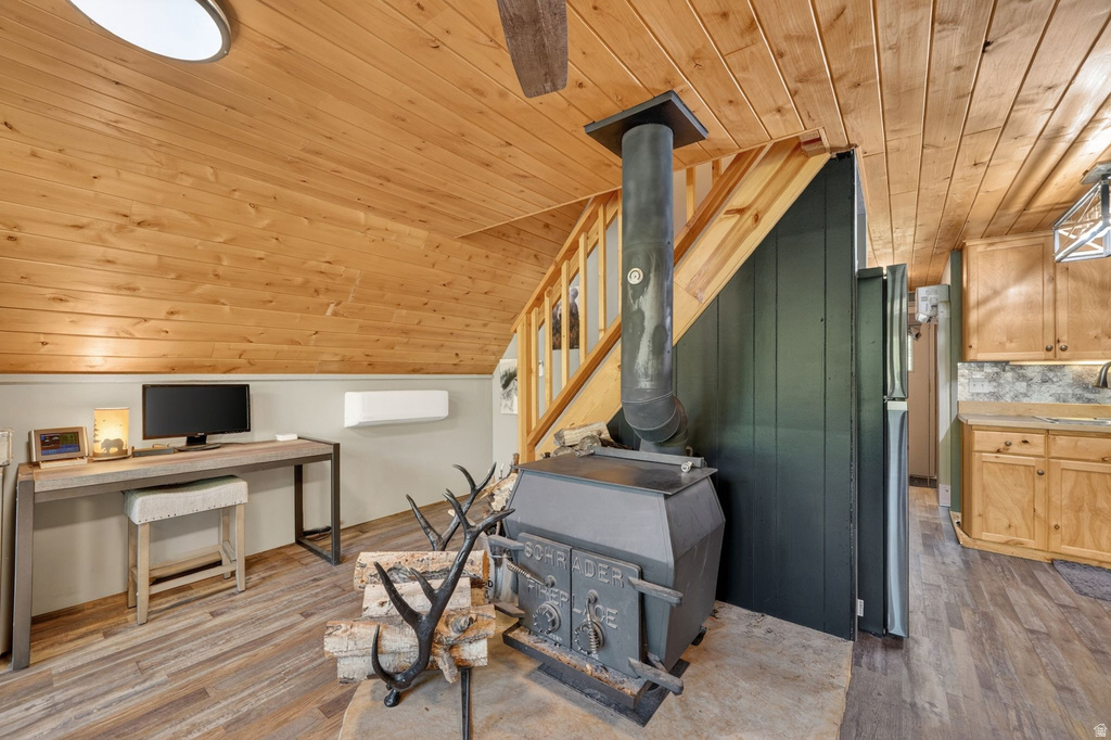 Wood-finish flooring and a wood-paneled ceiling complement the visible wood-burning stove