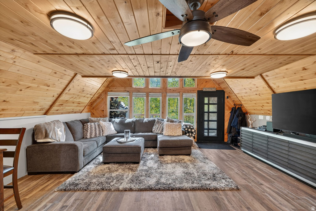 Spacious living area featuring sloped wood-paneled ceilings, wood-finish flooring, and a contemporary ceiling fan