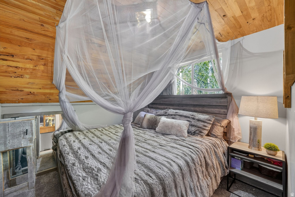 Loft bedroom featuring wood-paneled ceiling, a built-in wood headboard, and a large window