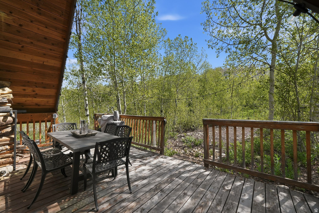 Expansive outdoor deck featuring wood flooring, a wood railing, and a rustic stacked stone accent wall