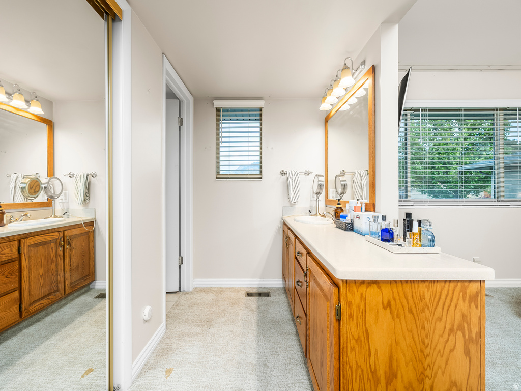 Dual vanity with wood-finish cabinetry, light countertops, and individual mirrors