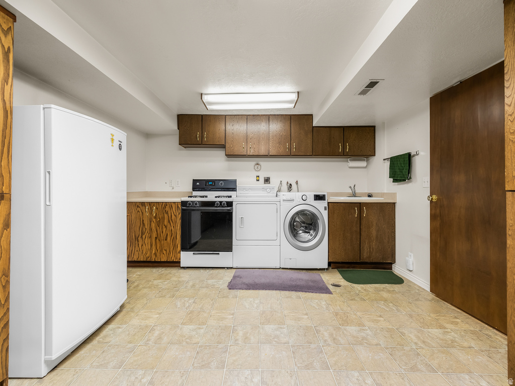 Functional utility space featuring a full-size refrigerator, electric range, washer, and dryer