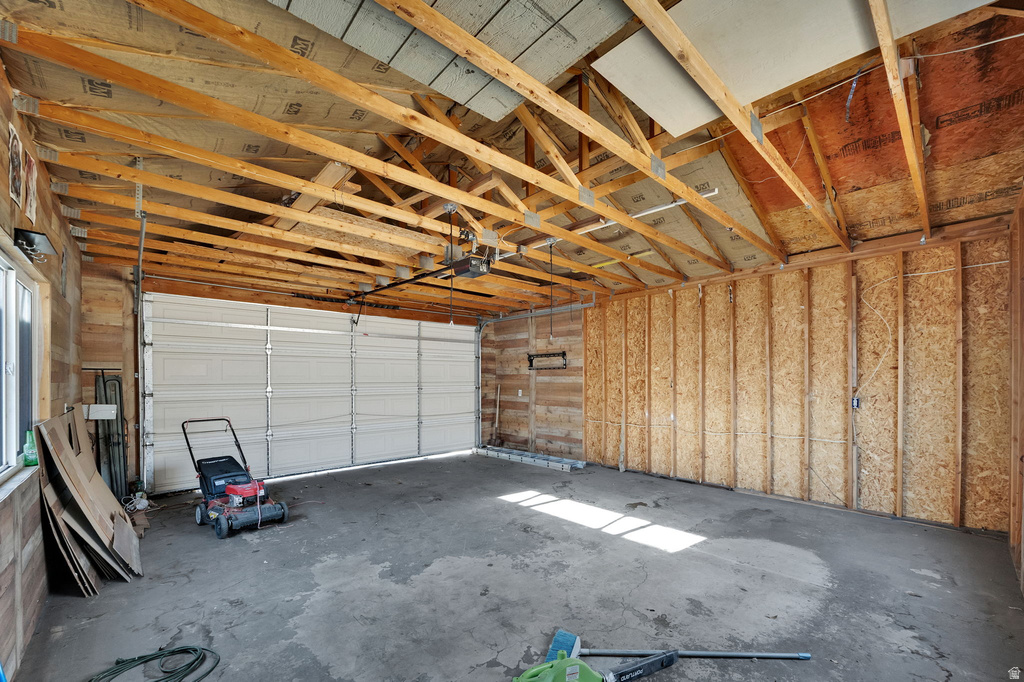 Spacious garage with exposed wood ceiling beams, concrete flooring, and a large overhead door