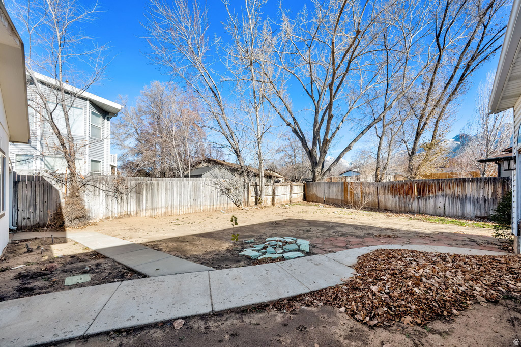 Enclosed backyard featuring a concrete pathway, a flagstone patio, and mature trees