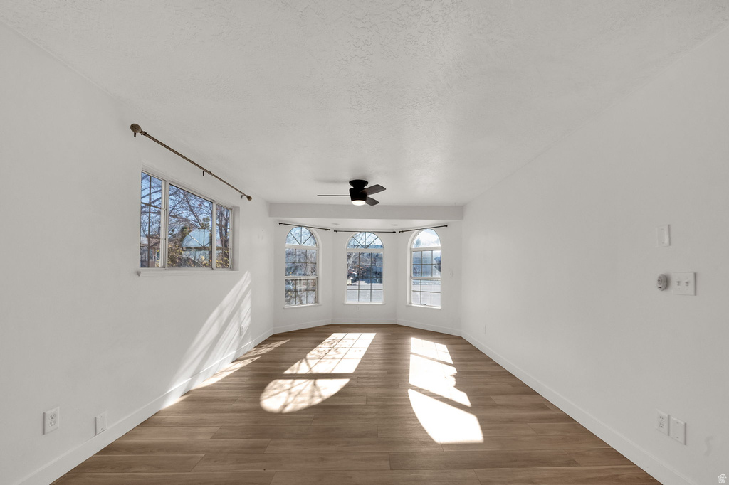 Wood-finish flooring throughout, white walls, and a ceiling-mounted fan fixture
