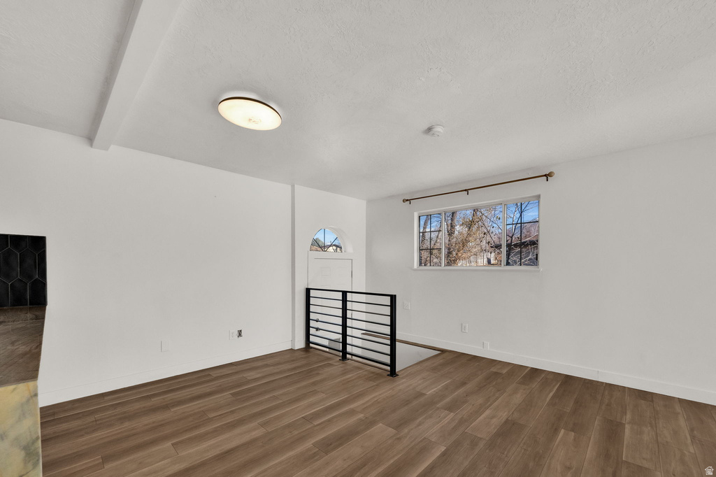 Wood-finish flooring, white walls, black metal railing, and a window with natural light