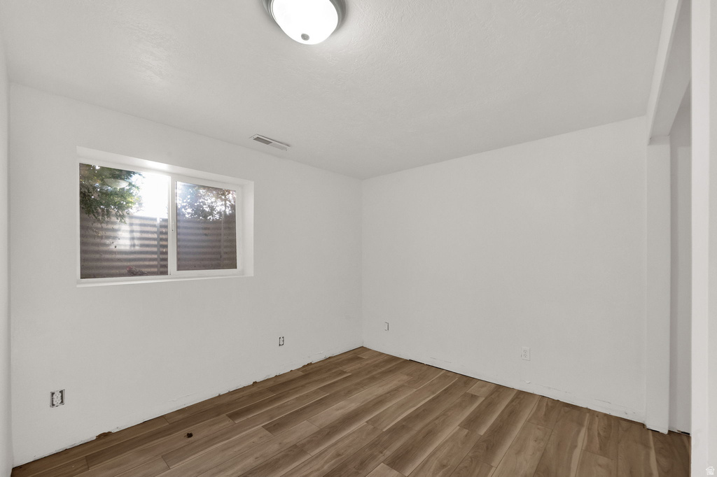 Wood-finish flooring, white walls, and a window with a window well