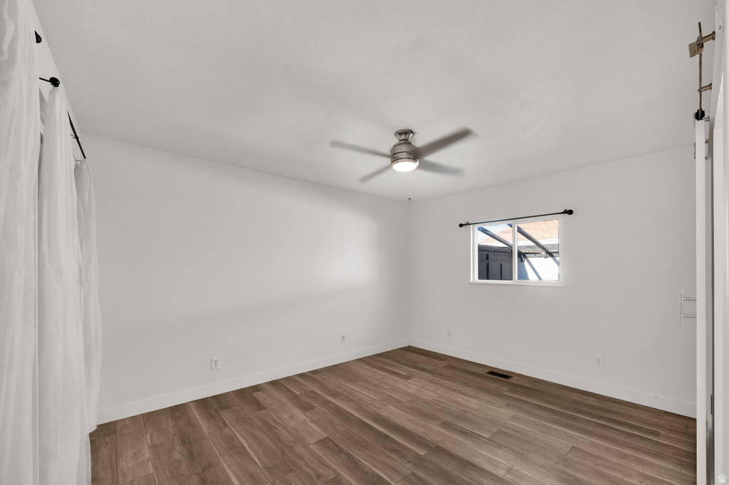 Wood-finish flooring, white walls, and a ceiling fan with integrated lighting