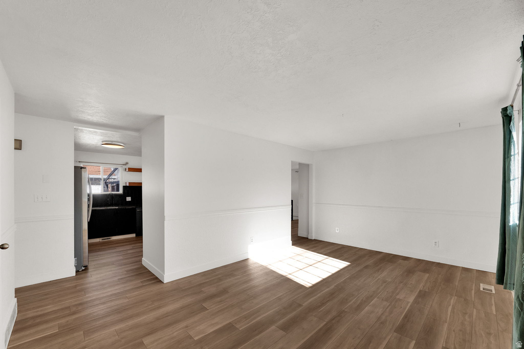 Wood-finish flooring, white walls, and a window with vertical blinds