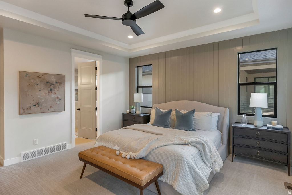 Bedroom featuring a tray ceiling with recessed lighting and a ceiling fan, a shiplap accent wall, two large windows, and neutral carpet flooring