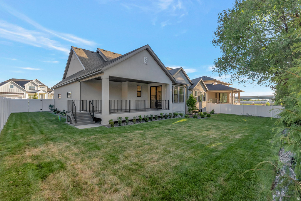 Spacious backyard featuring a manicured lawn, full privacy fencing, and a covered patio with dark railing