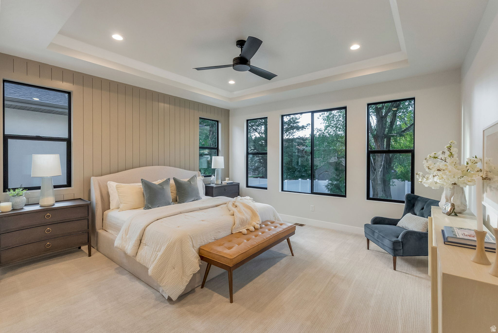 Spacious room featuring a tray ceiling with recessed lighting and a ceiling fan, a prominent accent wall with vertical paneling, and multiple black-framed windows