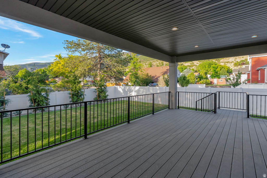 Covered deck with composite decking, black metal railings, recessed lighting, and a slatted ceiling