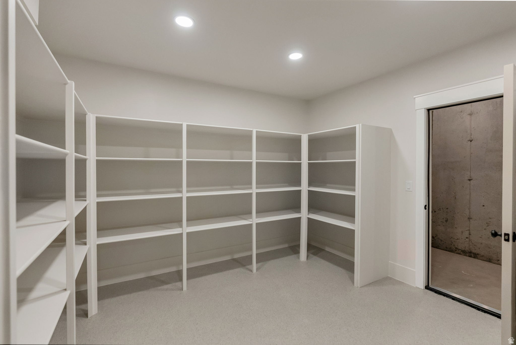 Spacious pantry featuring extensive built-in shelving, recessed lighting, and light-toned carpeting