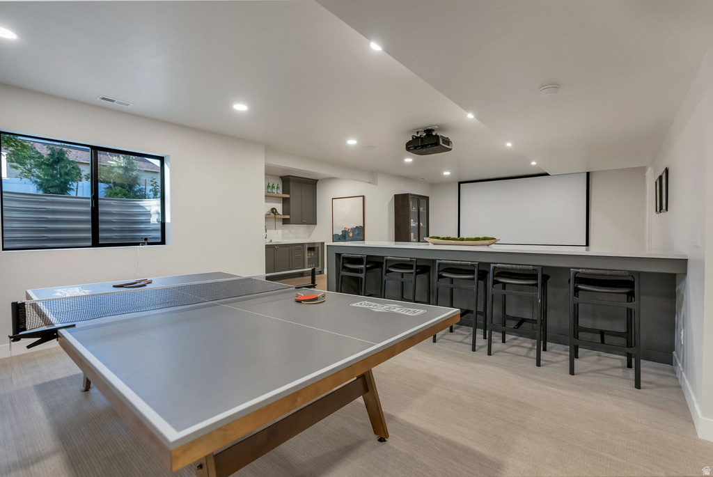Spacious entertainment room featuring recessed lighting, a built-in wet bar with a light-toned countertop, a ceiling-mounted projector, and a large projection screen