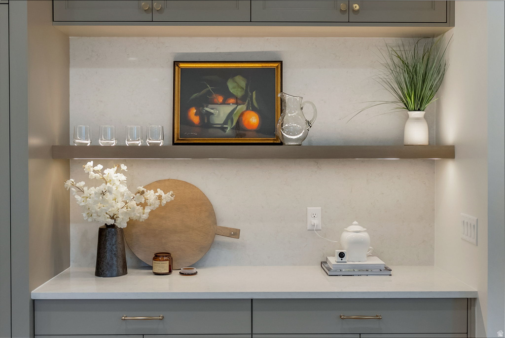 Built-in cabinetry with brass hardware, a floating wood-finish shelf, and under-cabinet lighting
