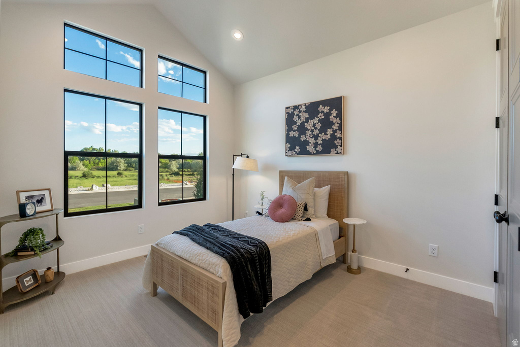 Vaulted ceiling bedroom featuring large black-framed windows, recessed lighting, and light-toned carpeting