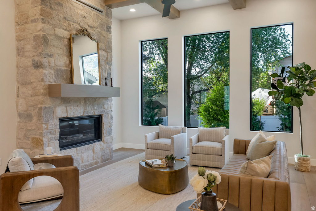 Living space featuring a stone-clad fireplace with a neutral mantel, tall ceilings, and three floor-to-ceiling windows