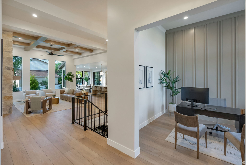 Open-concept living area with wood-finish flooring, a stone column, and a coffered ceiling with exposed beams