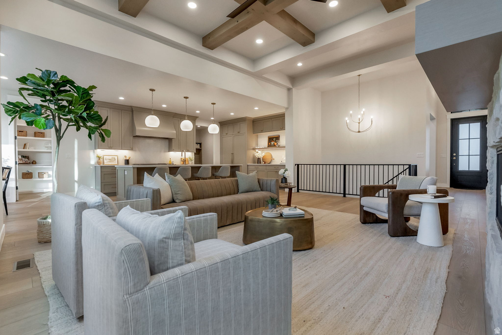 Open-concept living area featuring high ceilings with exposed wood beams, a stone-front fireplace, and wood-finish flooring