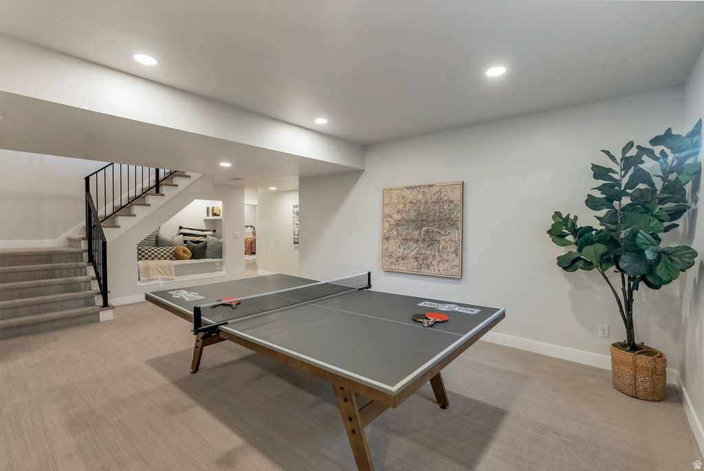 Spacious recreation room featuring recessed lighting, light-toned carpeting, and a built-in window seat under the staircase