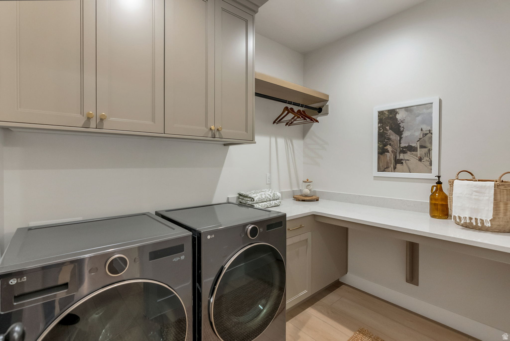 Dedicated laundry space featuring a side-by-side washer and dryer, upper cabinetry with brass hardware, a long counter workspace, and a floating wood shelf with a hanging rod