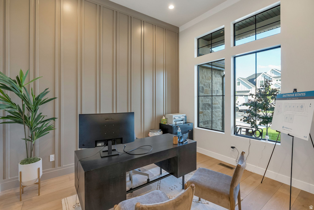 Architectural accent wall with vertical paneling, light wood-finish flooring, recessed lighting, and large multi-pane windows