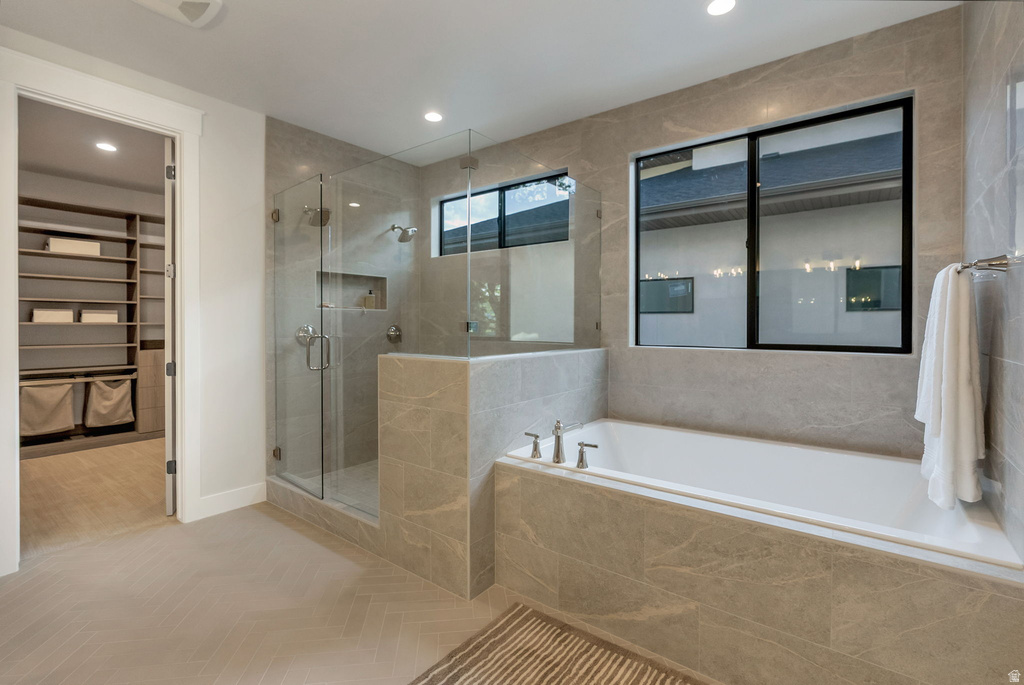 Spacious bathroom with a walk-in shower featuring a glass enclosure and built-in niche, alongside a large soaking tub