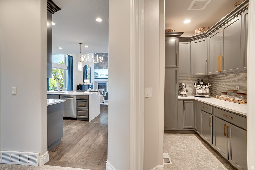 Dedicated pantry space featuring extensive gray cabinetry, gold-tone hardware, and white countertops