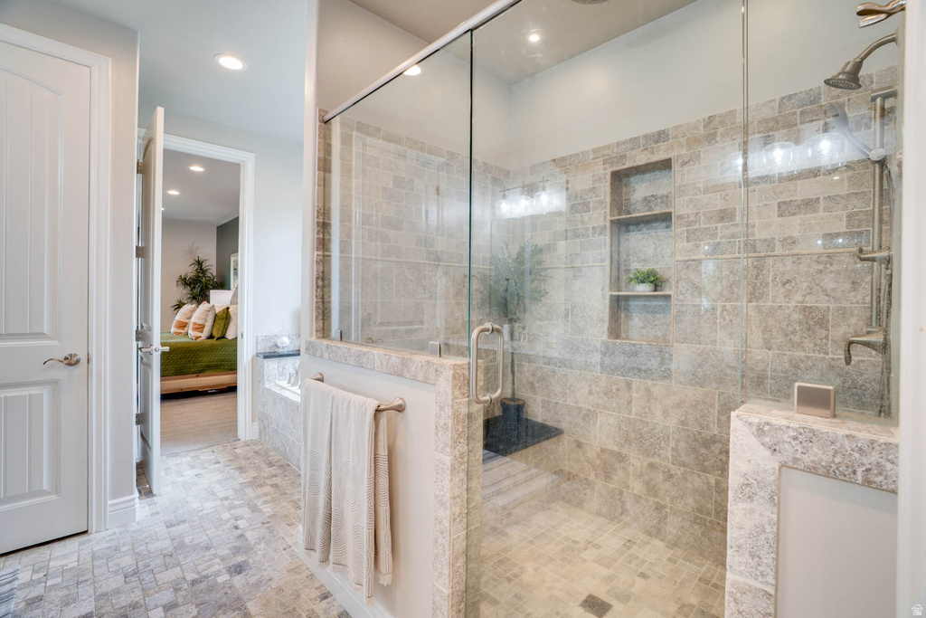 Walk-in shower featuring a glass enclosure, tile surround, integrated shelving, and a built-in bench