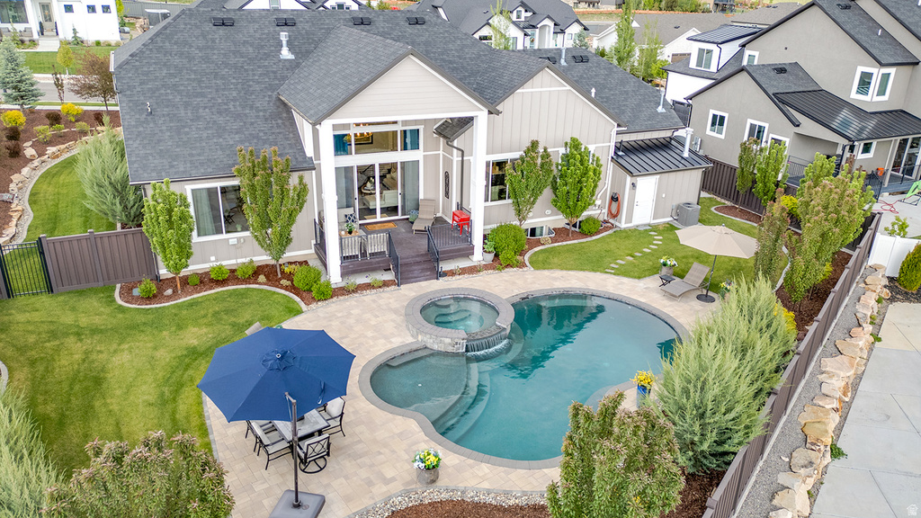 Expansive backyard featuring a custom-shaped swimming pool with an integrated spa, a paved patio, a wood-finish deck, meticulously landscaped garden beds, and a detached storage shed