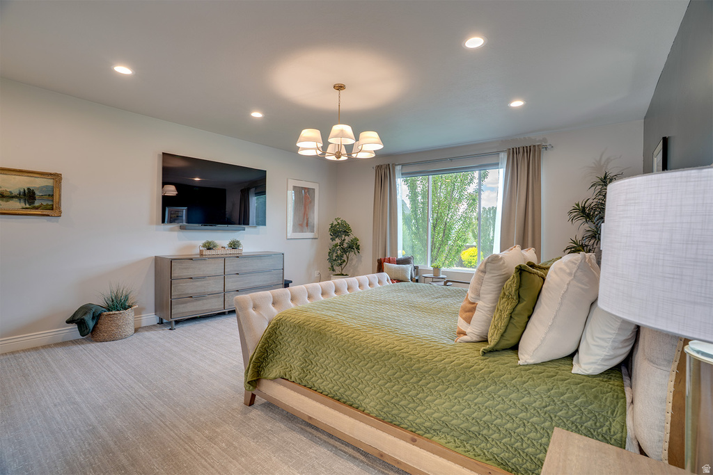Spacious bedroom featuring light-toned carpeting, a built-in window seat, recessed ceiling lighting, a five-light chandelier, and a large window with exterior views