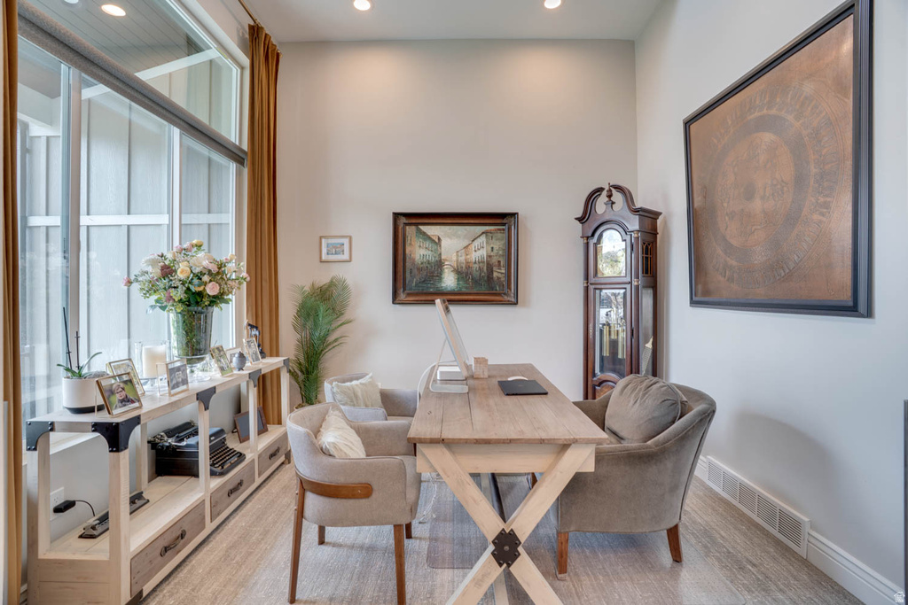 Spacious room with high ceilings, recessed lighting, expansive windows with roller shades, wood-finish flooring, and a built-in shelving unit