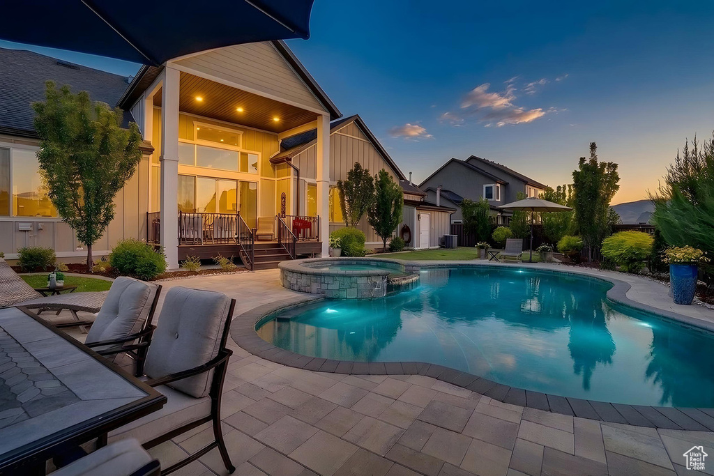Outdoor living space featuring a freeform swimming pool, integrated spa with stone surround, and a spacious paver patio