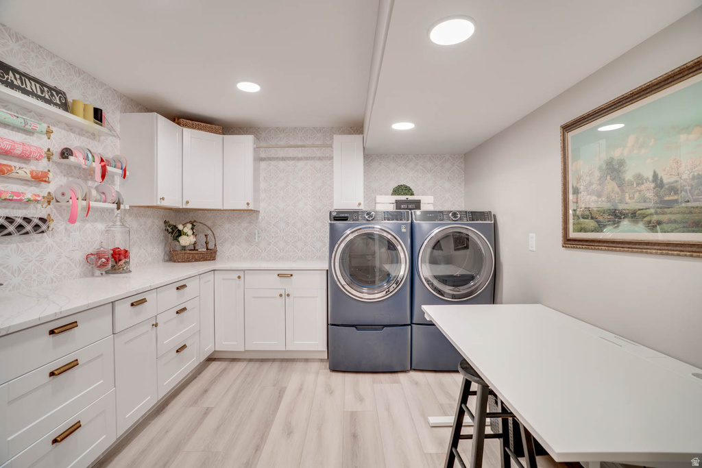 Utility room featuring extensive white cabinetry with bronze hardware, a light-toned wood-finish floor, recessed lighting, and a patterned wall covering