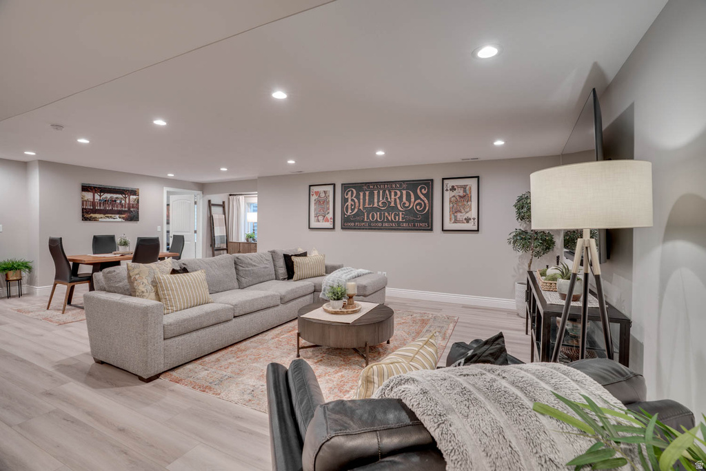 Open-concept space featuring light wood-finish flooring, recessed lighting, a neutral color palette, and a dedicated dining area with a dark wood table