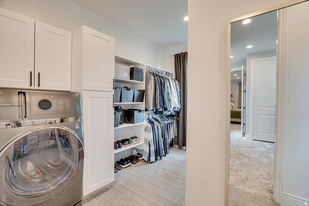 Integrated laundry area featuring stacked appliances and white shaker-style cabinetry