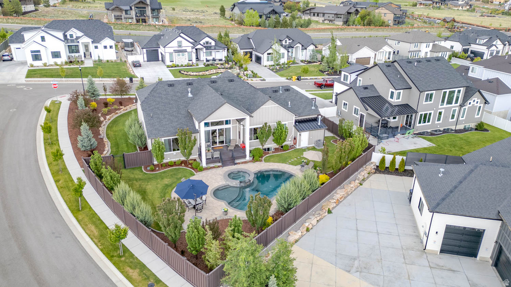 Expansive property featuring a unique curvilinear swimming pool with integrated spa, bordered by a privacy fence and mature landscaping